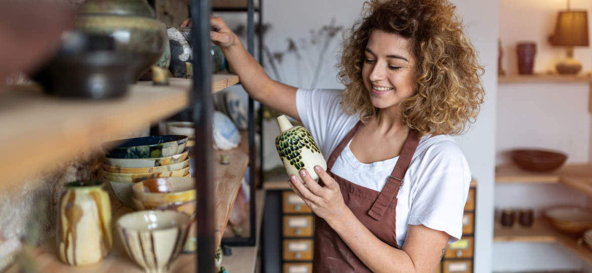 employee holding pottery in store and smiling