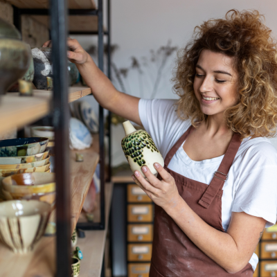 employee holding pottery in store and smiling